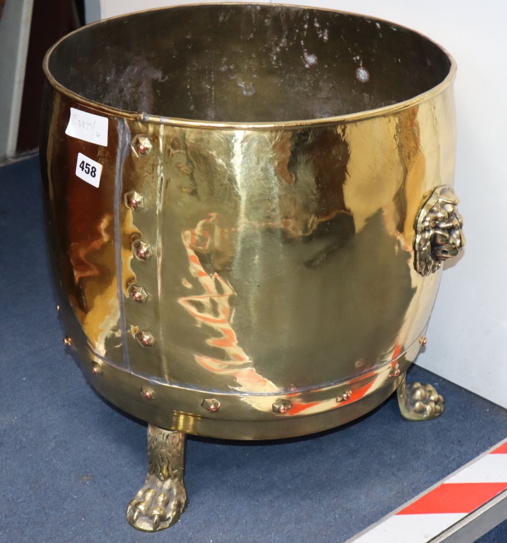 A brass log bin with paw feet and lion handles